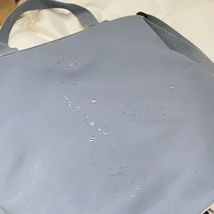 Casual light blue canvas crossbody bag with water repellent surface for daily student use.