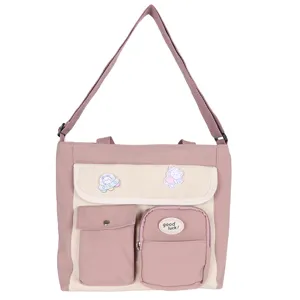Pink canvas crossbody bag detail, multi-pocket design with cute bear patches and strap.