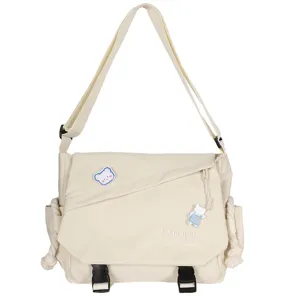 Canvas messenger bag detail showing adjustable strap, cute bear patch and front pocket.