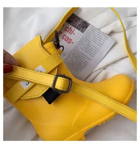 Détail de sac à bandoulière créatif en forme de botte jaune, montrant un design unique.
