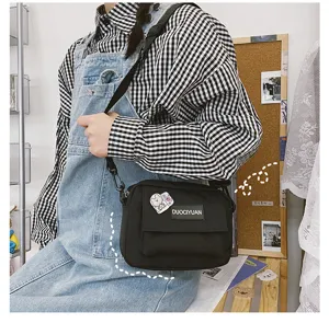 Vista detallada del bolso cruzado negro de lona, estilo casual para uso diario y urbano.