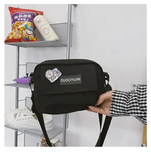 Bolso cruzado negro de lona con solapa y lindo pin de oso para uso diario escolar.
