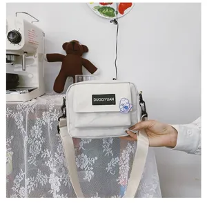 Detalle de bolso bandolera de lona blanca, bolso pequeño informal estilo Harajuku con parche lindo.