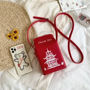 Primo piano di una borsa a tracolla in ecopelle rossa con stampa di pagoda bianca e scritta.
