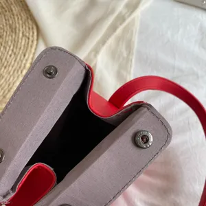 Primo piano della borsa a tracolla pagoda strutturata, ecopelle rossa e bottoni a pressione.