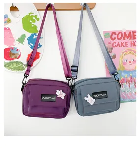 Vista detallada de bonitos bolsos cruzados de lona para estudiantes con bolsillo y insignias.