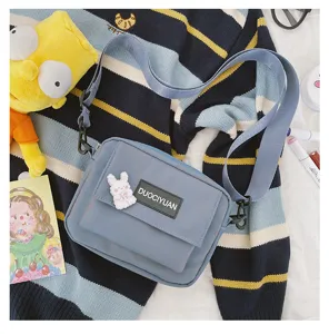 Vista detallada del bolso bandolera azul casual con lindo pin de conejo y correa ajustable.