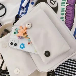 Detalle de bolso bandolera blanco minimalista con cierre magnético y funda de teléfono linda.