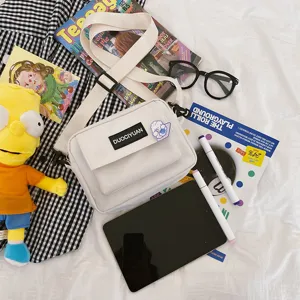 Bolso bandolera blanco de lona con bolsillo con solapa y etiqueta de marca para uso diario.