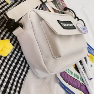 Detalle del bolso mensajero blanco que muestra bolsillo con solapa y parche de logo.