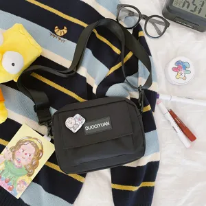 Vista detallada de bolso cruzado negro de lona con bolsillo delantero para estilo diario.