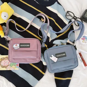 Vista detallada de bolsos cruzados de nailon de estilo japonés informal en rosa y azul ajustable.