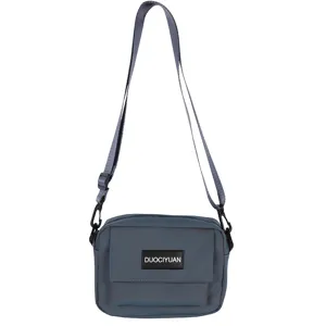 Detalle del bolso cruzado gris azulado con correa ajustable y bolsillo frontal con solapa.