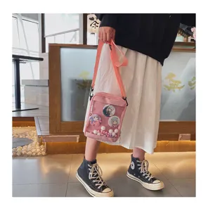 Vista detallada de un bolso ita rosa con bolsillo frontal transparente y chapas de anime lindas.
