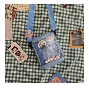 Detalle de bolso cruzado de malla transparente con insignias de anime y lona azul.