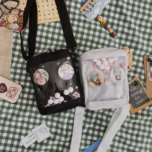 Detalle del bolso bandolera transparente con bolsillo frontal y lindos pines de anime exhibidos.
