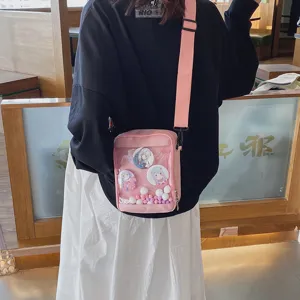 Vista detallada de un bolso ita rosa transparente con pines de anime y pequeñas bolas de colores.