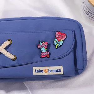 Blue canvas pencil pouch with alternative enamel pins and shoelace detail, aesthetic style.
