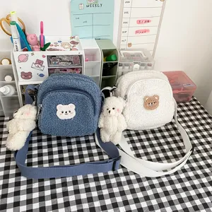 Detailed shot of cute lamb wool crossbody bag with fluffy bear patch and plush doll pendant.