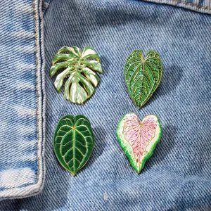 Tropical plant enamel pin set featuring monstera and caladium leaf designs for clothing and bags.