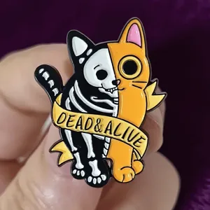 Close-up detail of Halloween dark style split cat enamel pin badge with cool aesthetic.