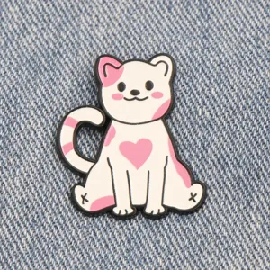 Détail en gros plan d'une jolie broche émaillée chat rose et blanc sur fond en denim.