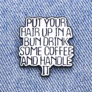 Gros plan détail d'un badge émaillé à citation de motivation créative accessorio vestimentaire.
