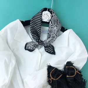 Detailaufnahme eines schwarz-weißen Seidenschals mit schickem Paisley- und Pünktchenmuster.
