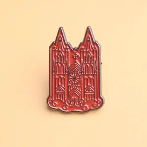 Detailed shot of a gothic cathedral enamel brooch, red metal badge for clothing or bags.