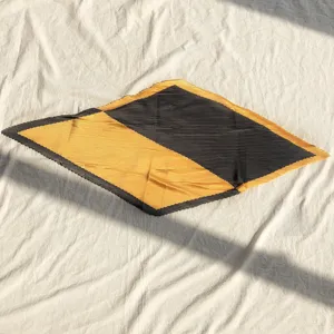 Detailed view of a fashionable pleated square scarf with black and yellow blocks.