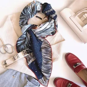 Detailed view of fashionable printed silk scarf styled with knitwear and accessories.