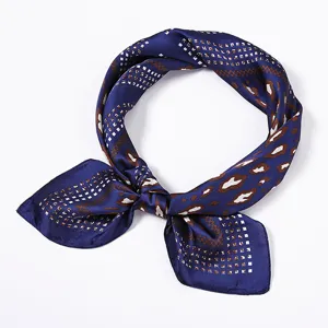 Detailansicht eines blauen, seidenähnlichen quadratischen Tuchs mit eleganten Mustern.