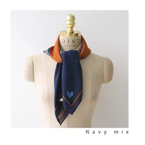 Detailed shot of a navy blue satin square scarf with orange border and heart pattern.
