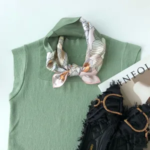 Grünes ärmelloses Stricktop kombiniert mit floralem Seidenschal für Damen Freizeitmode.