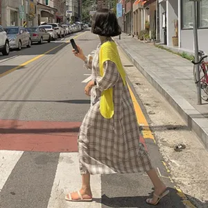 Stylish plaid long dress with yellow knitted shawl, perfect autumn street fashion outfit.