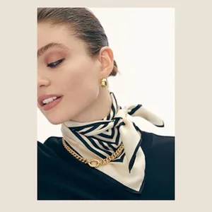 Detail view of a chic cream and black striped silk neck scarf worn elegantly by a model.