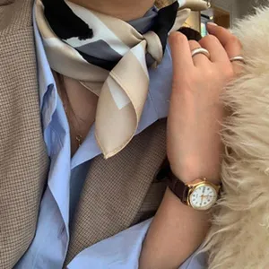 Detailansicht eines eleganten geometrischen Seidenhalstuchs mit stilvollen Beige-Schwarz-Blöcken.