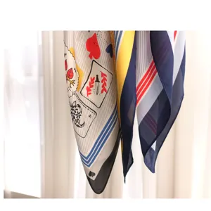 Close up view of women's printed silk scarf featuring creative playing card patterns and stripes.