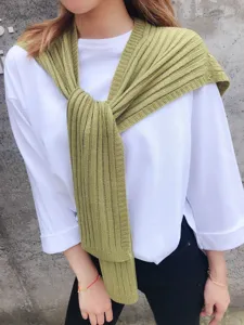 Detail shot of green knitted shawl accessory, textured rib knit design for autumn styling.