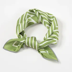 Close-up detail van de groene en witte geometrische patronen zijden sjaal met knoop.
