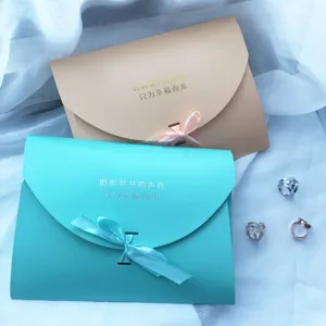 Nahaufnahme Detailansicht eleganter Umschlag-Geschenkboxen mit Schleifen und zarten Ringen.
