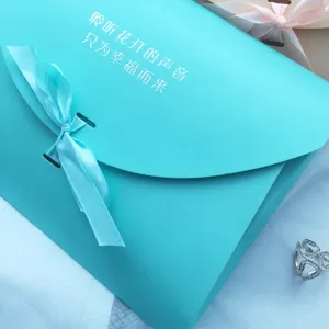 Turquoise envelope gift box with blue ribbon bow packaging for wedding favors and holiday gifts.
