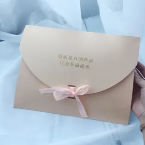 Close-up detail shot of beige envelope gift packaging bag with pink ribbon bow.