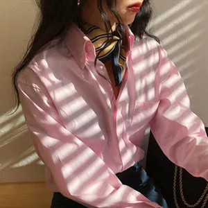 Detailansicht eines eleganten gestreiften Seidenschals kombiniert mit einem rosa Hemd als Accessoire.