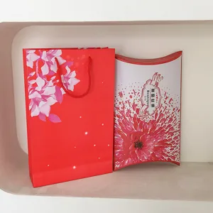 Gift packaging set including red paper bag and pillow gift box with floral design.