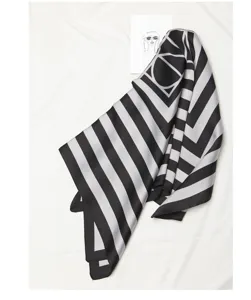 Close-up detail of the black and white striped silk scarf featuring geometric design.