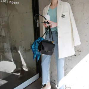 Schickes Seidentuch an schwarzer Handtasche, kombiniert mit weißem Blazer für Damen.