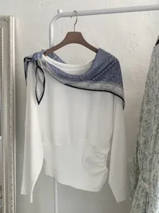 Detailansicht eines weißen Strickoberteils kombiniert mit blauer Paisley-Dreieckstuch.