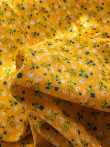 Nahaufnahme von gelbem Blumenstoff mit feiner Textur zeigt das Muster des Baumwolltuchs.