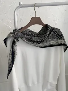 Detailansicht eines klassischen schwarz-weißen Paisleymuster-Seidenschals ordentlich aufgehängt.